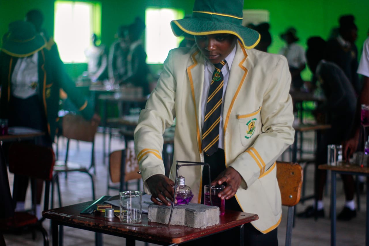 Learner in a cream blazer carrying out a science experiment