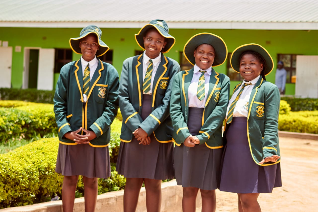 Form 1 to 4 learners in green blazers and sun hats